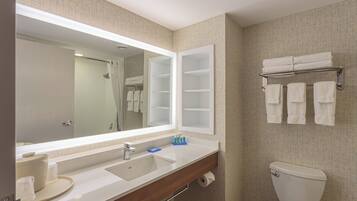 A bathroom with a large mirror, a sink, a toilet, and a towel rack.
