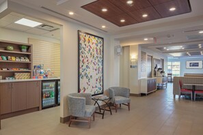 A hotel lobby with seating, a refreshment bar, and a wall with geometric artwork. - Holiday Inn Express & Suites Belleville by IHG (Belleville)