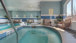Une piscine intérieure avec un bord carrelé, des chaises longues et une fenêtre offrant une vue agréable.