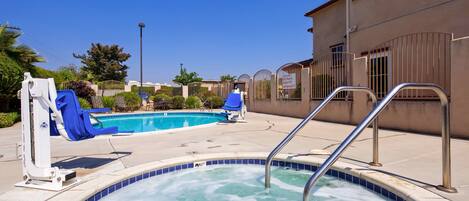 Una piscina con hidromasaje, sillas de descanso y un tobogán.