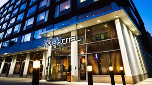 Un moderno edificio de hotel con fachada de vidrio y señalización iluminada que dice "Best Western Time Hotel".