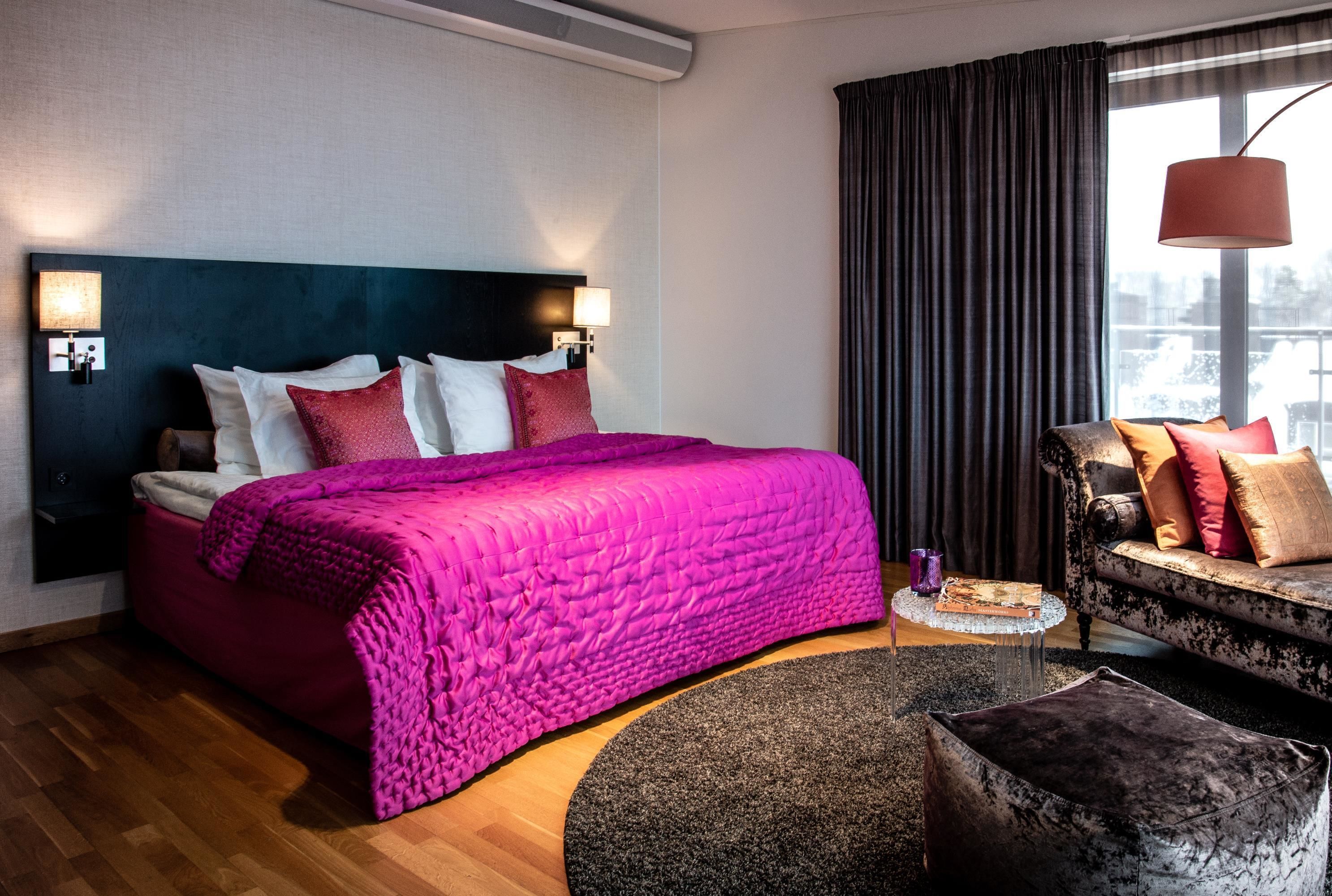 Une chambre d’hôtel avec un grand lit, un canapé et une fenêtre avec des rideaux.