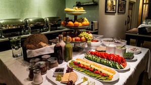 Una mesa de buffet con diversos alimentos, incluyendo frutas, verduras, quesos y salsas.