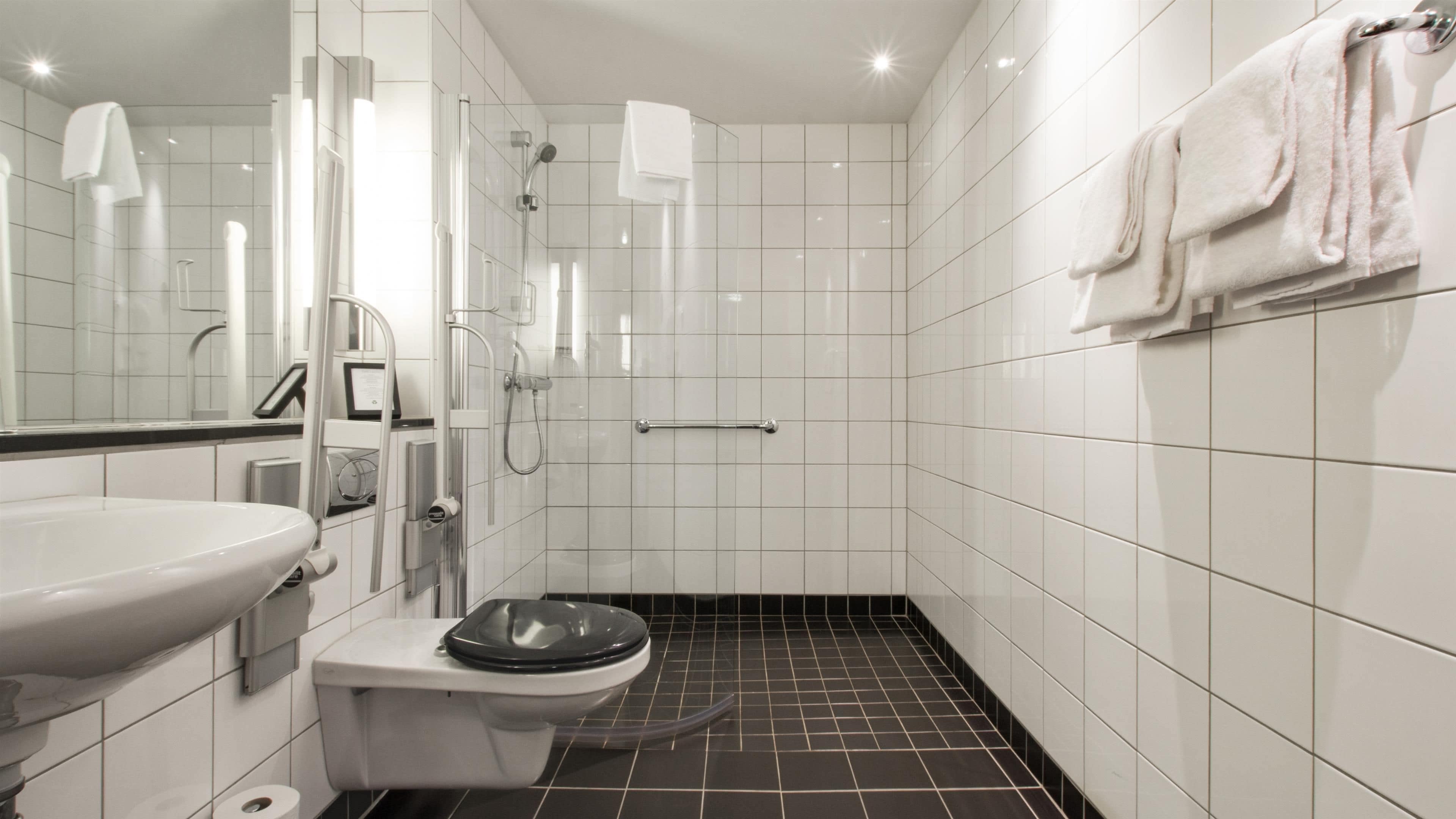Un baño moderno con lavamanos, inodoro y zona de ducha blancos.