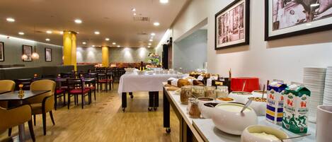 A restaurant with booths and tables, a buffet with various food items, and wall-mounted artwork.