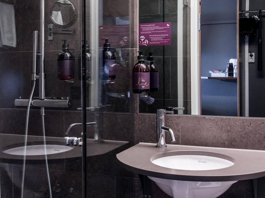 A modern bathroom with two sinks, a shower, and a glass-enclosed shower area.
