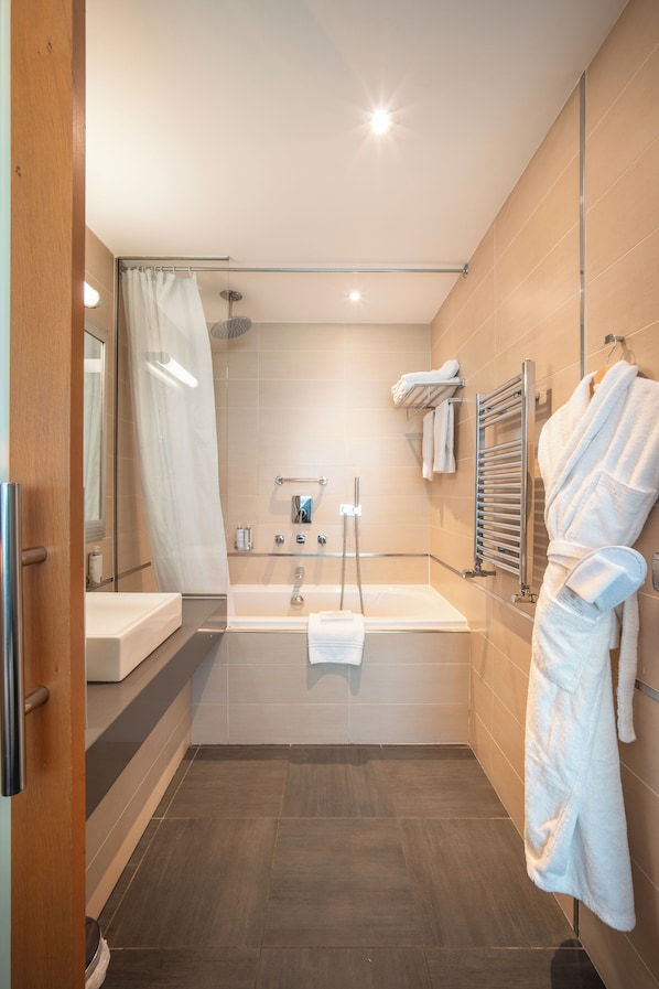 Un baño moderno con bañera, cabina de ducha de vidrio y un perchero para toallas.