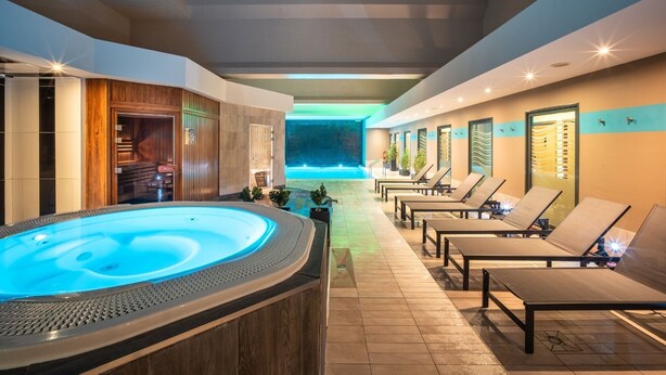 Un área de spa con un jacuzzi, sillones reclinables y una piscina.