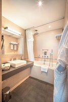 A modern bathroom with a sink, mirror, and shower.