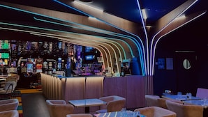 Un bar moderno con iluminación de neón, máquinas de juego y zonas de estar.