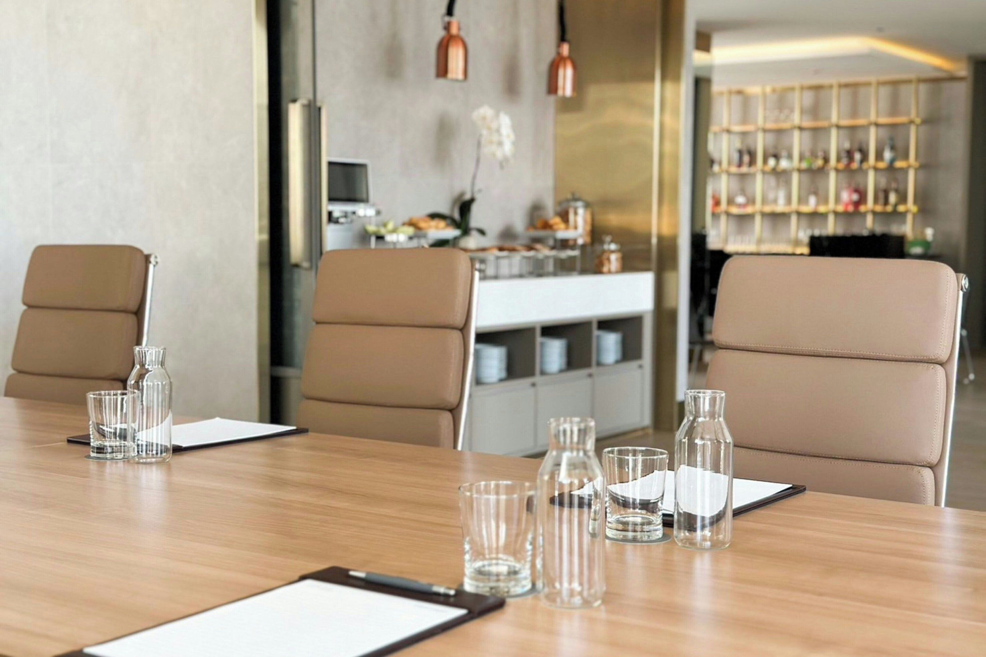 Una sala de conferencias moderna con una mesa de madera, dos sillas color beige y una pizarra.