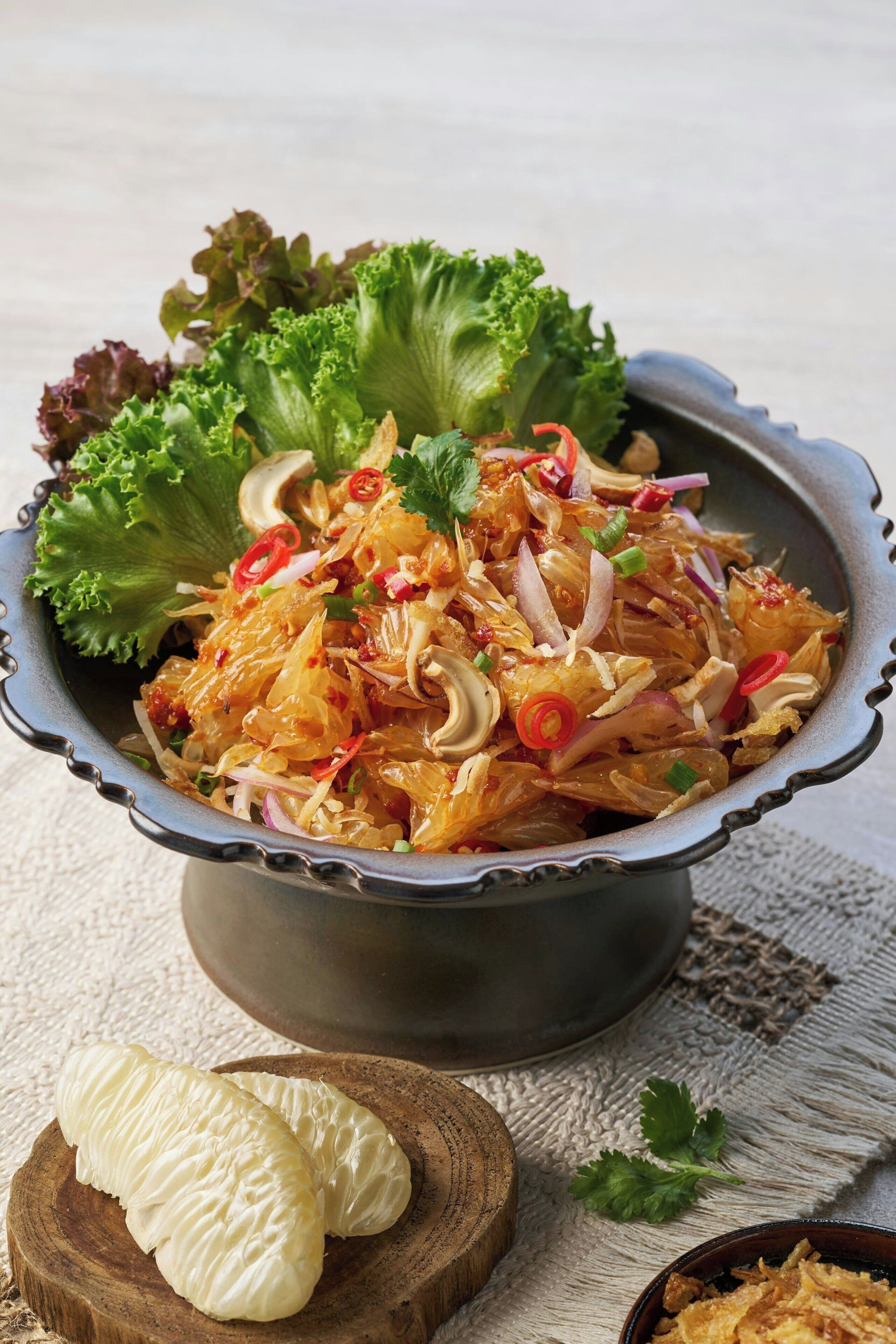Uma salada com alface e cebolas vermelhas fatiadas, decorada com fatias de pimenta vermelha e coentro.
