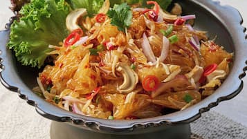 Uma salada com alface e cebolas vermelhas fatiadas, decorada com fatias de pimenta vermelha e coentro.