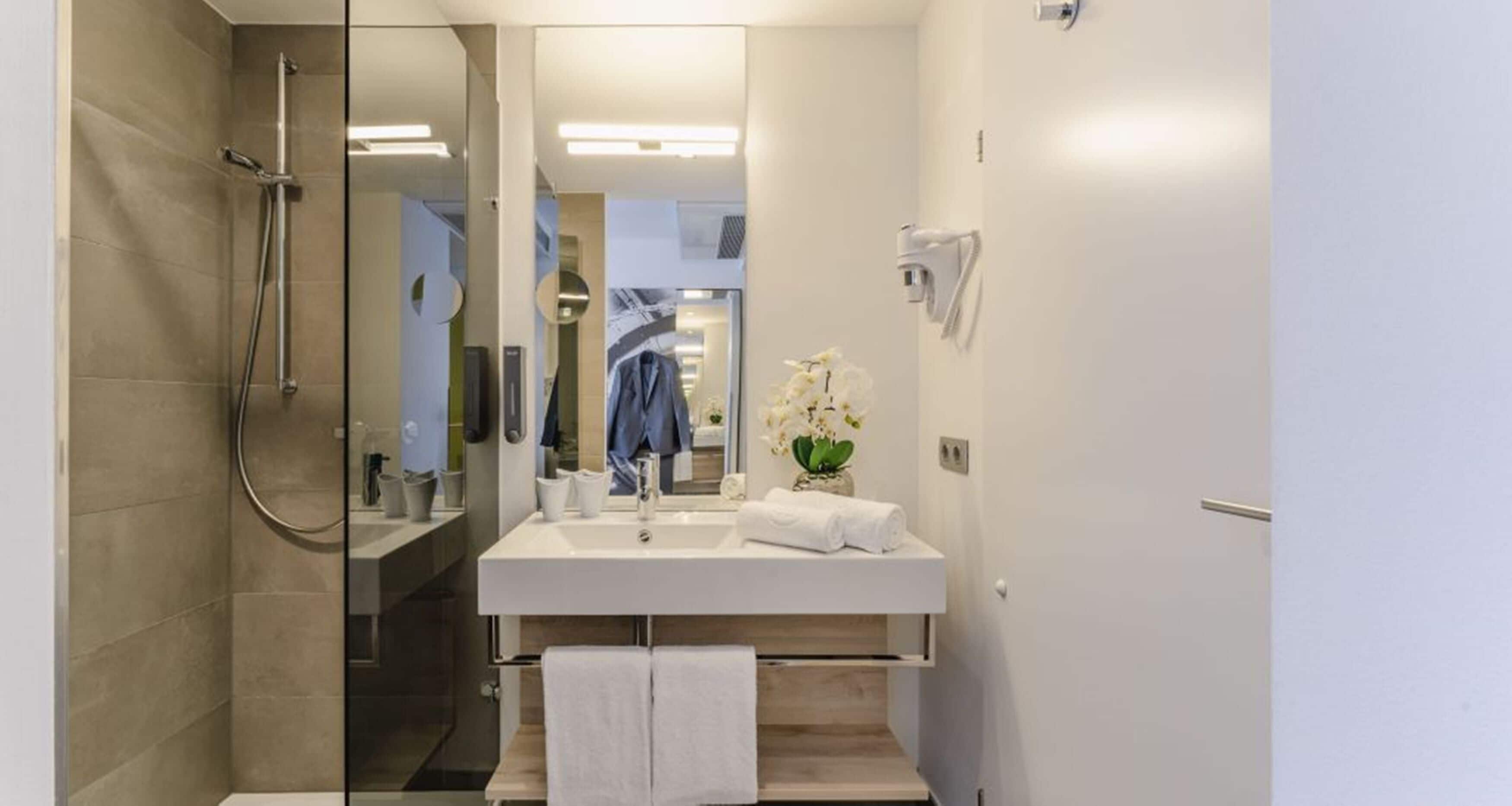 Ein modernes Badezimmer mit Dusche, Waschbecken und Spiegel.