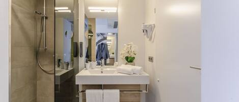 Un baño moderno con ducha, lavamanos y espejo.