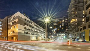 A modern hotel with multiple floors, a prominent entrance, and a well-lit street at night.