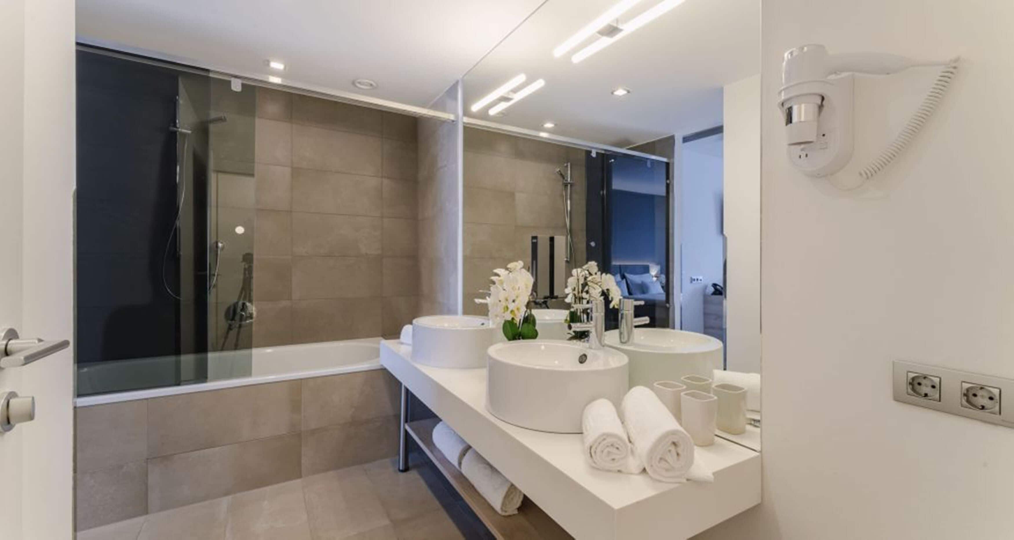 A modern bathroom with a glass-enclosed shower, two sinks, and a large mirror.