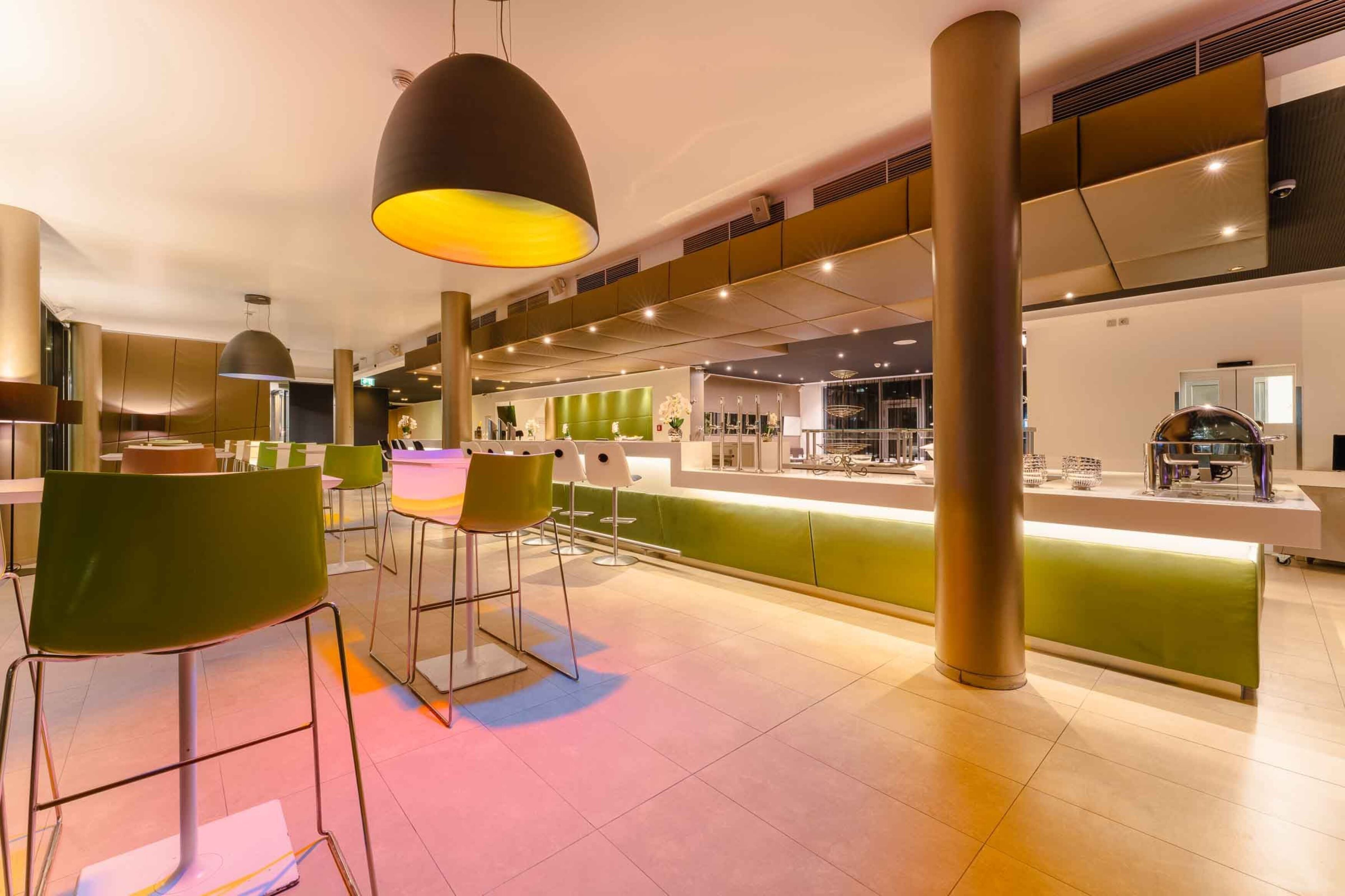 Un restaurant moderne doté de chaises hautes, d’un comptoir et d’un éclairage suspendu.