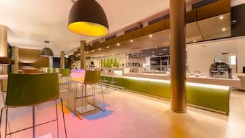 Un restaurant moderne doté de chaises hautes, d’un comptoir et d’un éclairage suspendu.