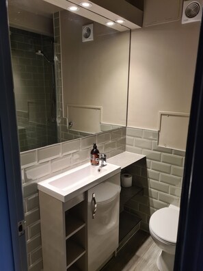 A modern bathroom with a white sink, a mirror, and a toilet.