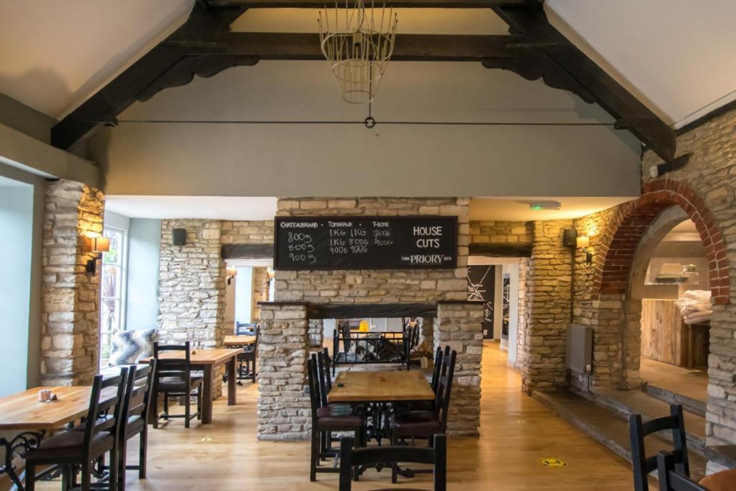 Un restaurante con paredes de piedra, mesas de madera y un menú en una pizarra.