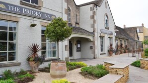 The Priory Inn with a stone facade, a well-maintained garden, and outdoor seating area. - The Priory Inn (Tetbury)