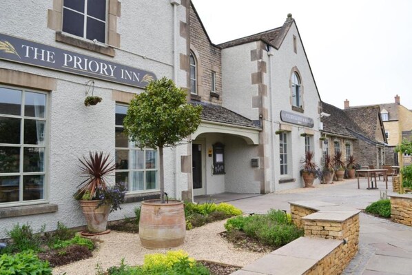The Priory Inn with a stone facade, a well-maintained garden, and outdoor seating area.