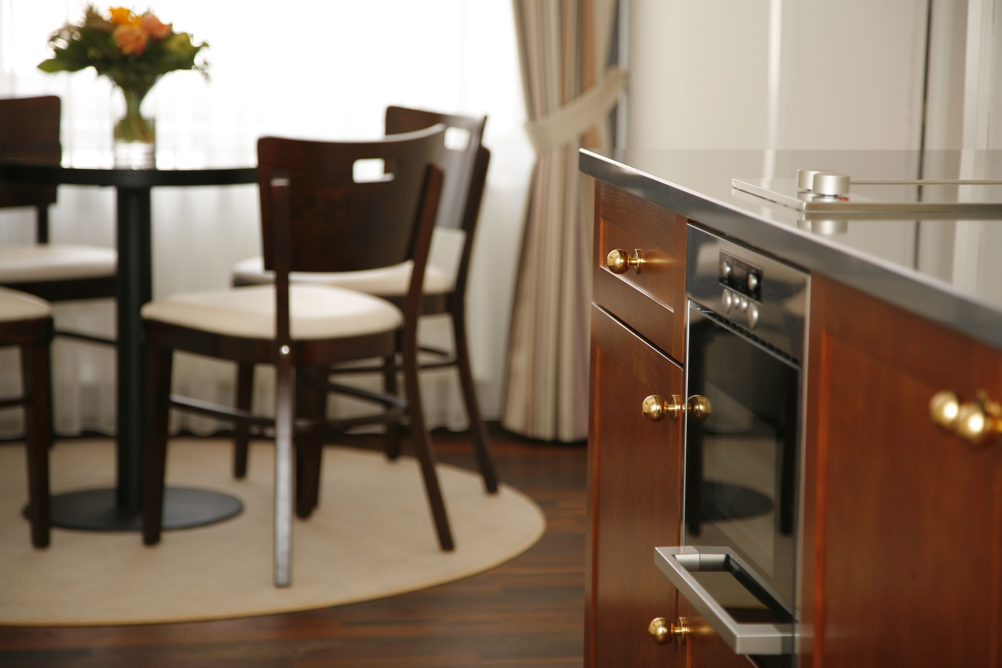 Een moderne keuken met houten kastjes, een inbouwoven en een eethoek met een tafel en stoelen.