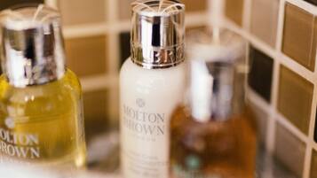 Three bottles of cologne on a reflective surface with a tiled wall in the background.