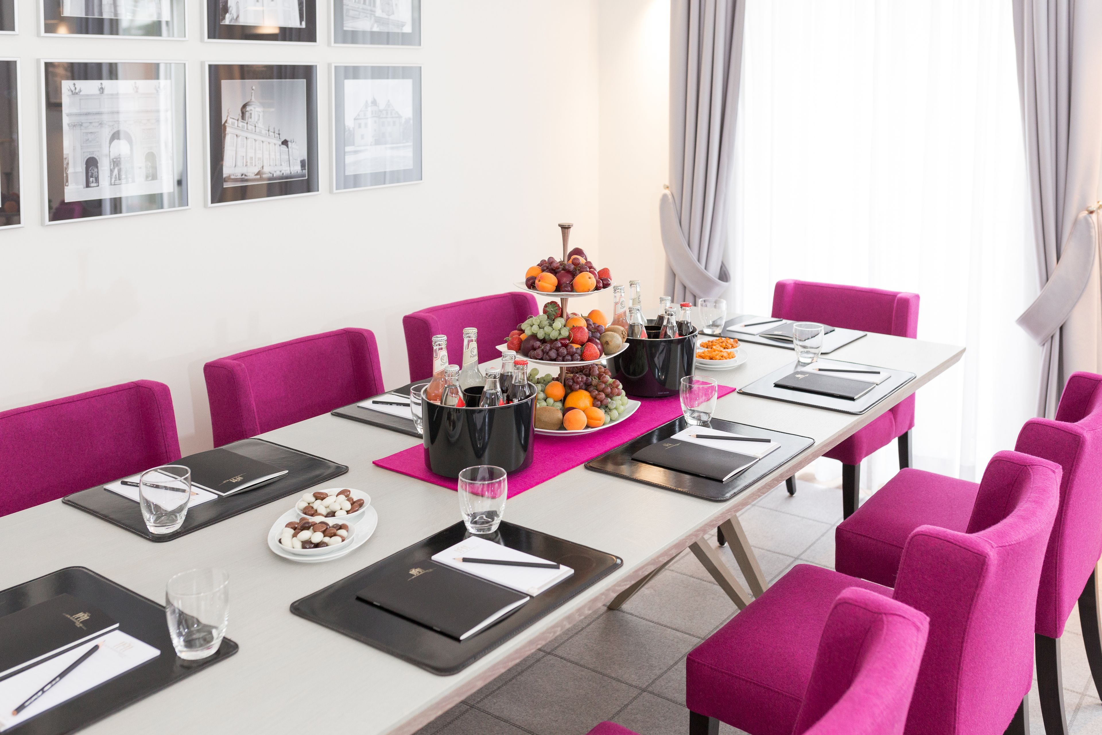 A conference room with a long table set for a meeting, equipped with nameplates, water glasses, and a fruit platter.