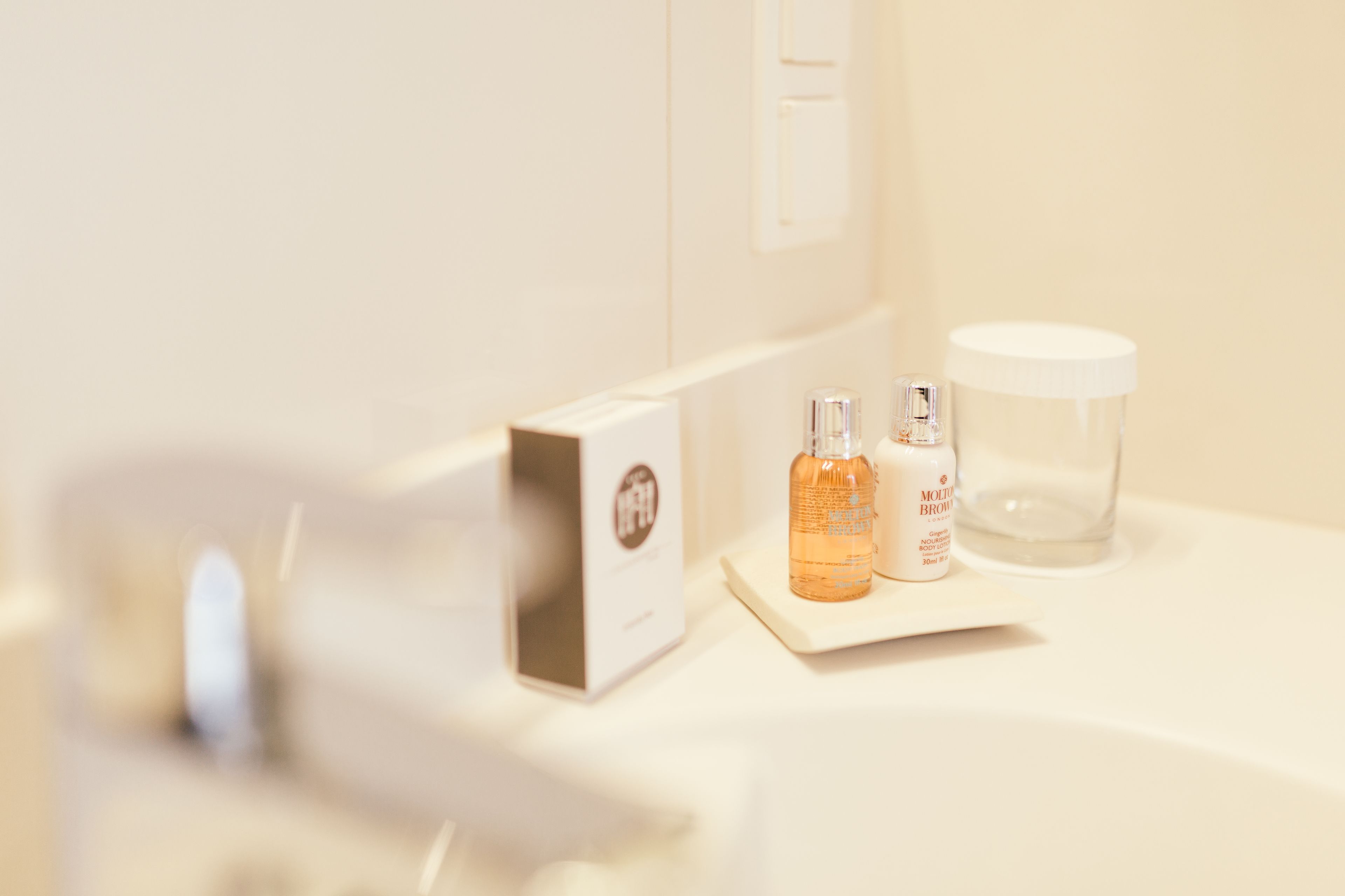 Un meuble-lavabo avec une boîte blanche, deux bouteilles et un récipient en verre.