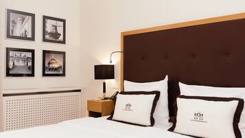 Ein Hotelzimmer mit einem großen Bett, einem hölzernen Kopfteil und vier gerahmten Bildern an der Wand.