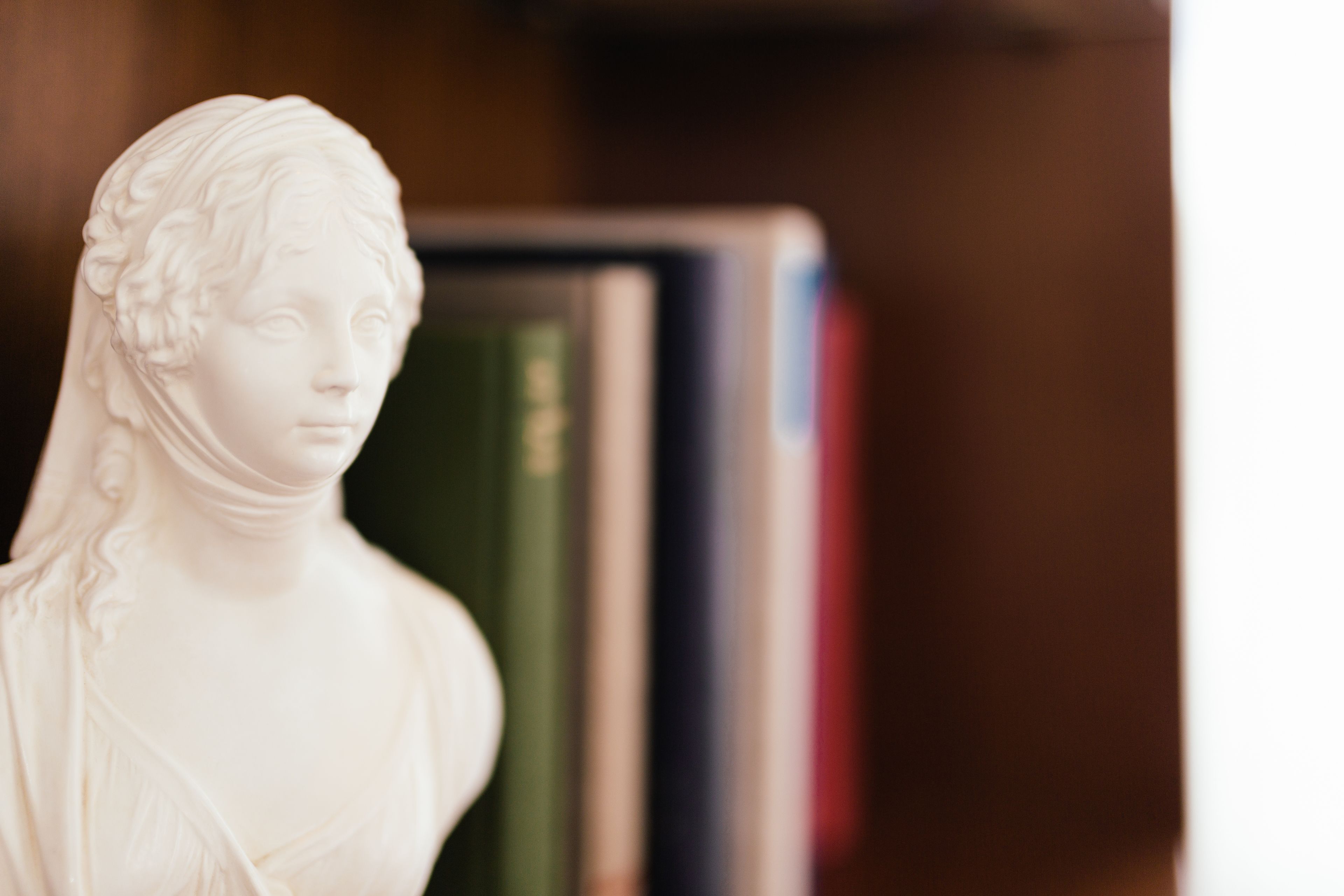 Eine Büstenstatue vor einem Bücherregal.