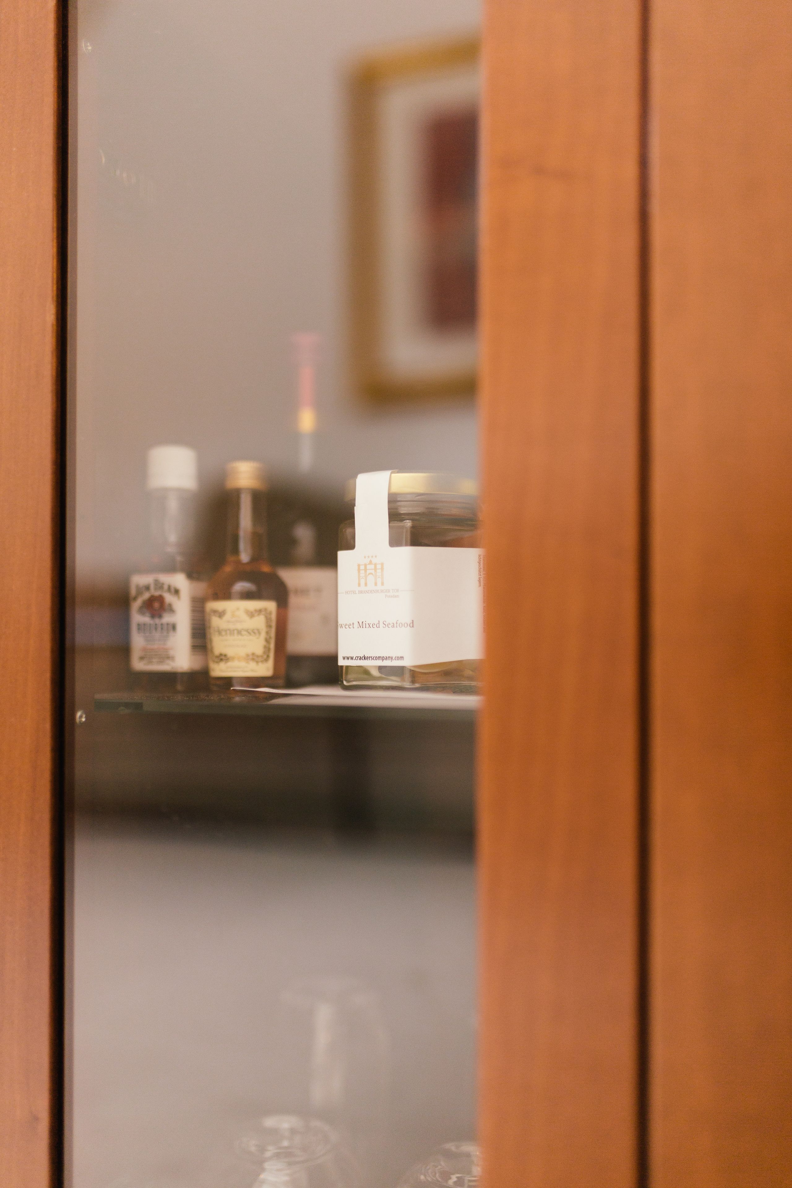 A wooden door with a mirror reflecting a shelf containing bottles and a box.