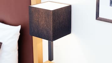 Uma mesa de cabeceira de madeira com uma luminária preta, um travesseiro branco e um quadro na parede.