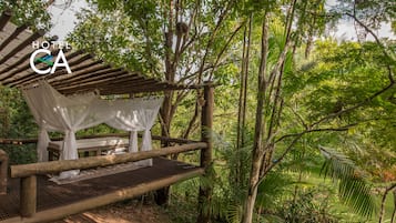 A wooden structure with a canopy, surrounded by lush greenery.