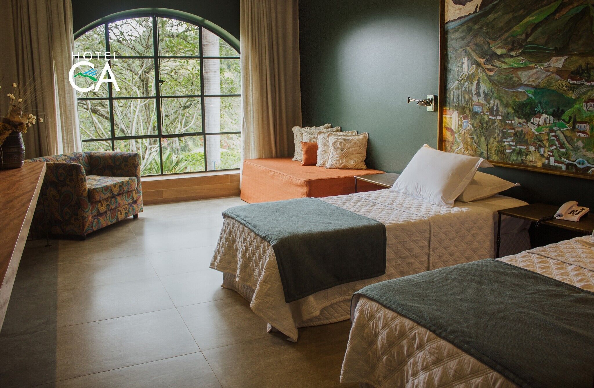 Habitación de hotel con dos camas, un sofá, un escritorio y un ventanal con cortinas.