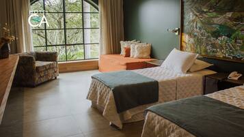 Habitación de hotel con dos camas, un sofá, un escritorio y un ventanal con cortinas.