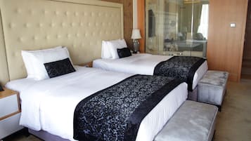 A hotel room with two beds, a large tufted headboard, a mirror, and a wooden door.