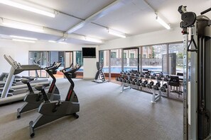 Une salle de sport équipée de tapis de course, de vélos elliptiques et d’une série de haltères.