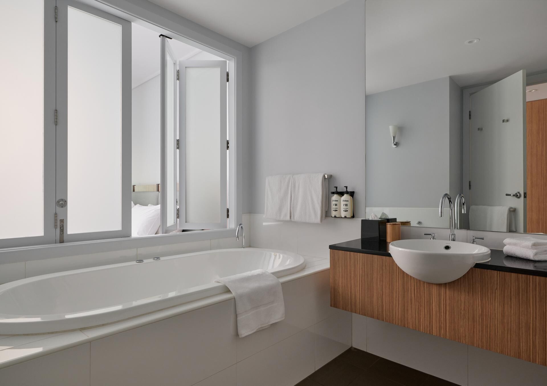 A modern bathroom with a freestanding bathtub, a wooden vanity, and a large mirror.