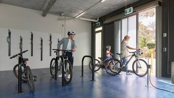 Un amplio espacio interior para ciclismo con varias bicicletas, piso de concreto y un gran ventanal que deja entrar luz natural.