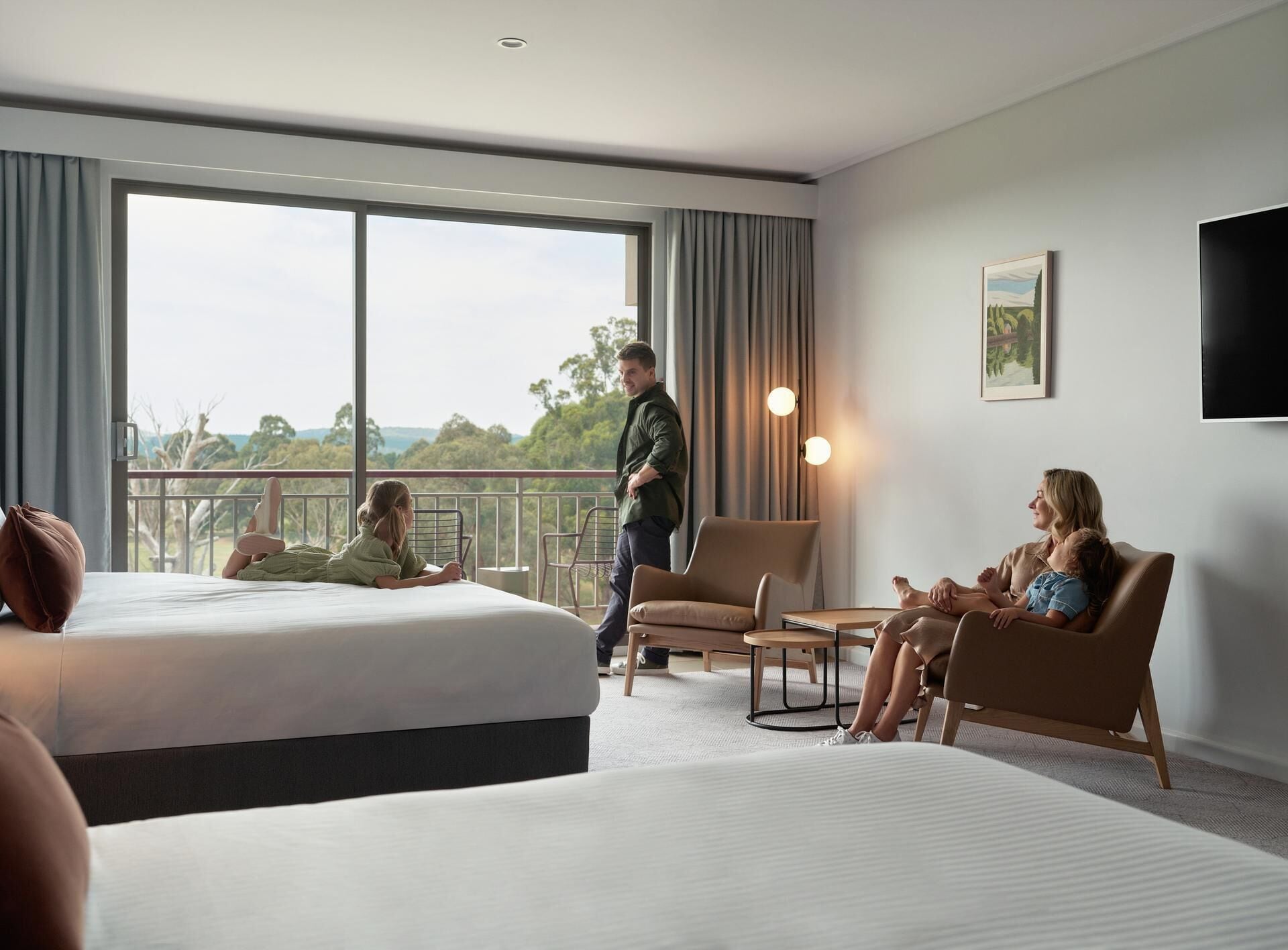 Une chambre d’hôtel avec une grande fenêtre, un lit, un canapé et un fauteuil.