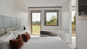 A modern bedroom with a large bed, a built-in bathtub, and a balcony with a view of the outdoors. - RACV Goldfields Resort (Creswick)