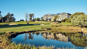 A golf course with a pond, a building with multiple floors, and surrounding greenery. - RACV Goldfields Resort (Creswick)