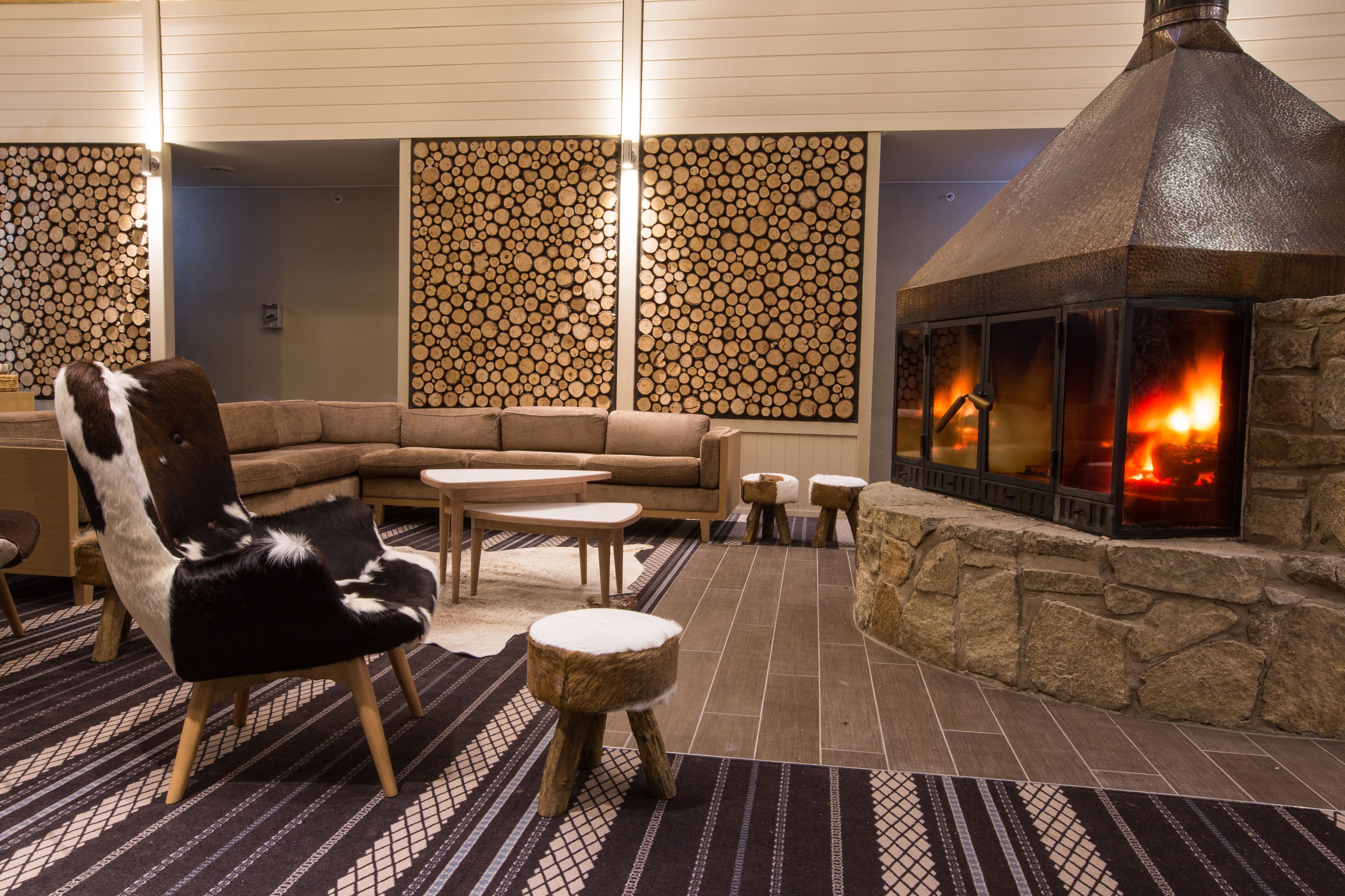Una zona de estar acogedora con chimenea de piedra, un sillón de cuero, un sofá y una mesita.