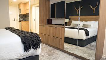 Ein Schlafzimmer mit einem Bett, einem Spiegel, einem Kleiderschrank, einem Fernseher und einer Wanddekoration mit einem Hirschkopf.