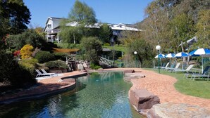 A clear swimming pool with a brick pathway, lounge chairs, and umbrellas. - The Sebel Pinnacle Valley Resort (Merrijig)