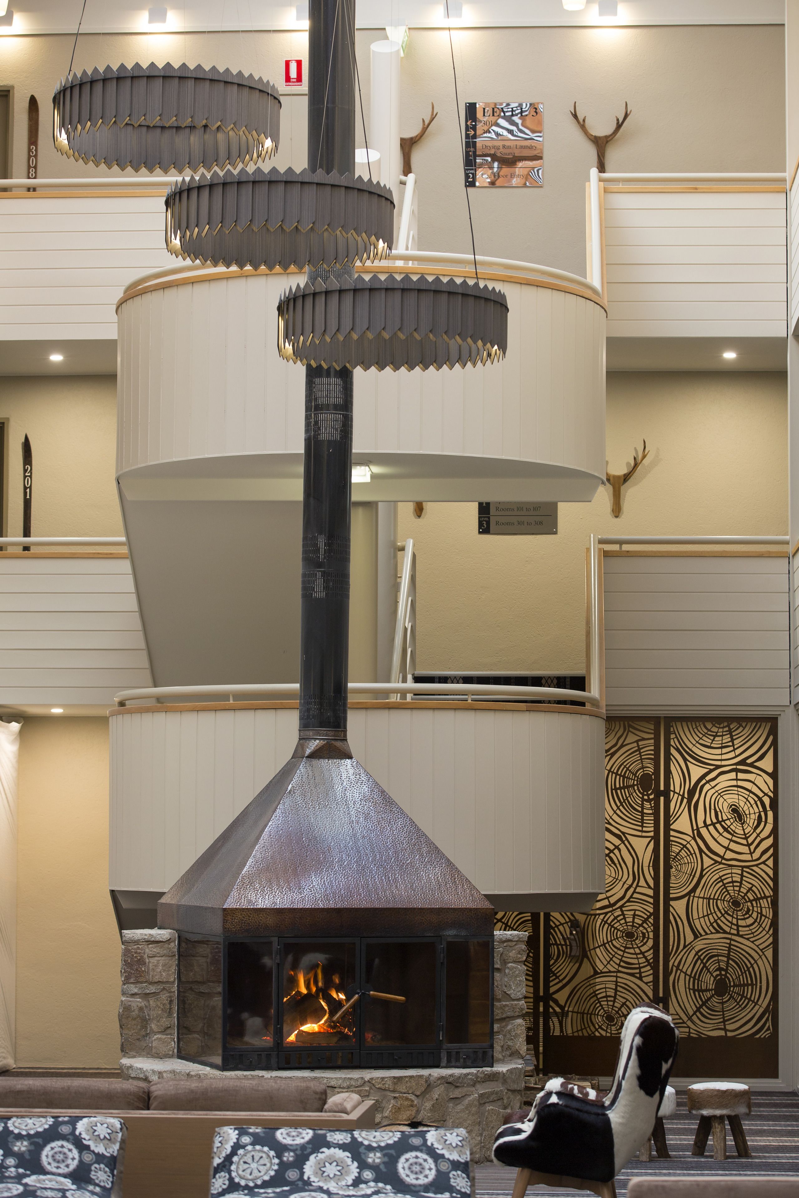 A modern interior with a central fireplace, tiered seating, and decorative antlers on the wall.