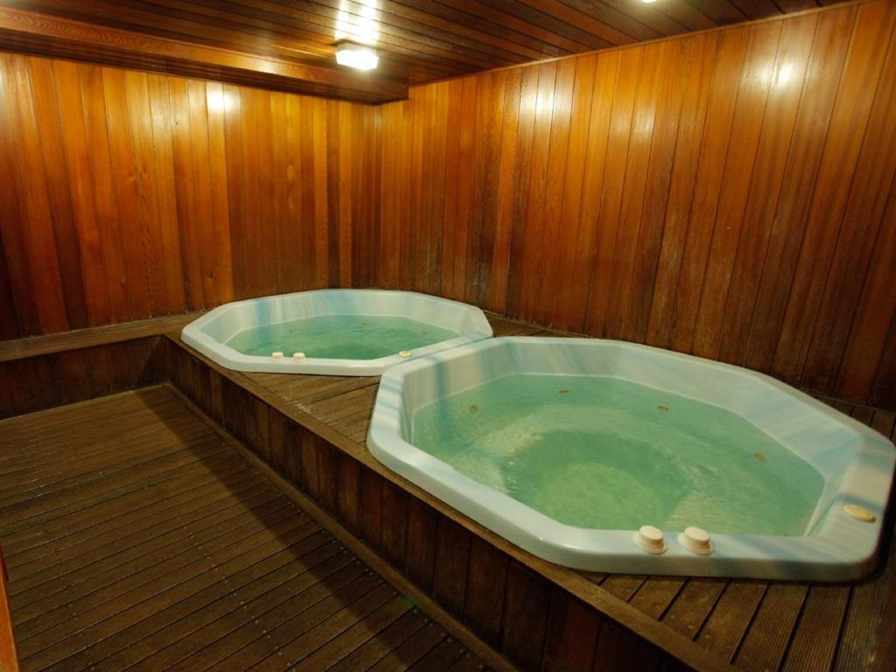 Zwei Whirlpools in einem Holzraum mit Holzboden.